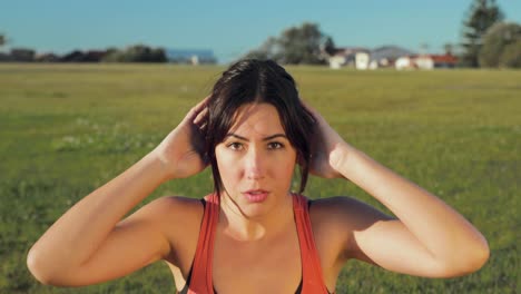 vista frontal de una mujer euroasiática mientras hace abdominales en el parque.