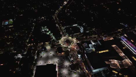 nighttime aerial drone view of a roundabout with steady vehicular traffic