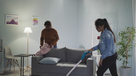 multiracial friends clean living room together on weekend