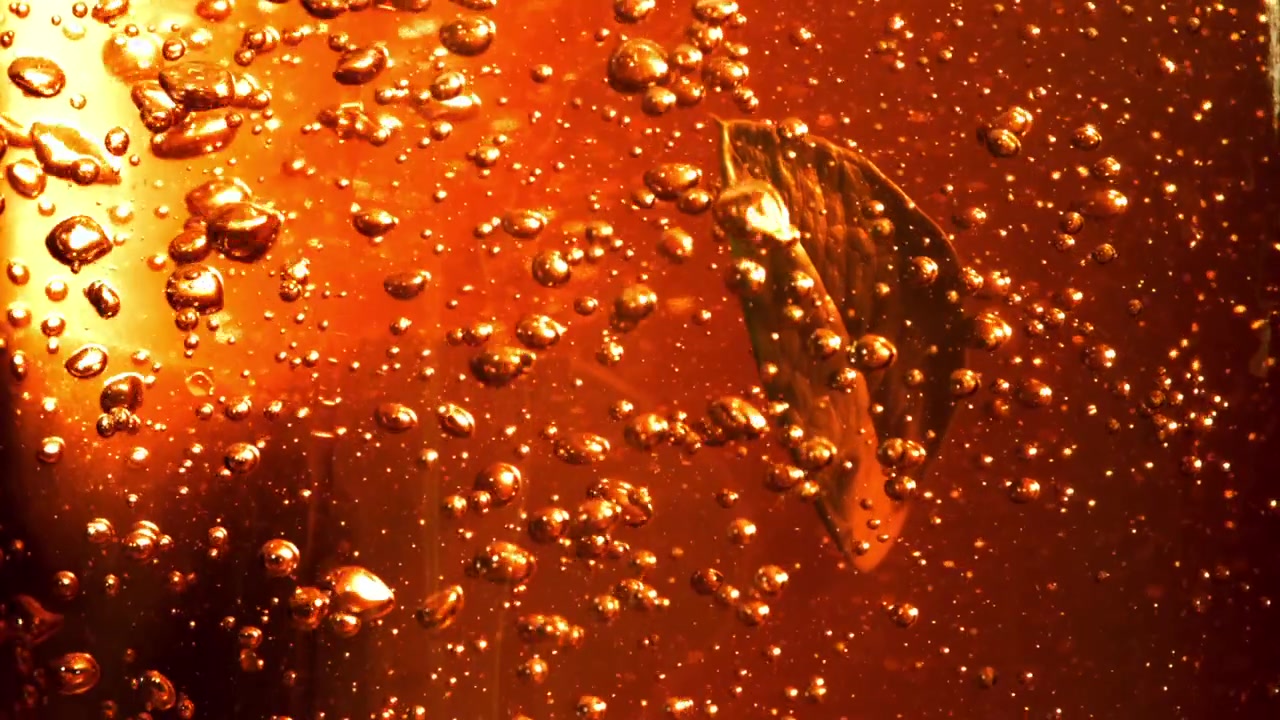 Foglia verde che affonda in un liquido arancione dorato con bolle