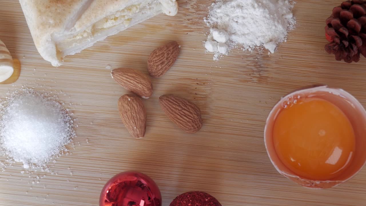 Smooth zoom out of traditional Spanish Pan de Cádiz ingredients including almonds, sugar, flour, and egg yolk on a wooden board