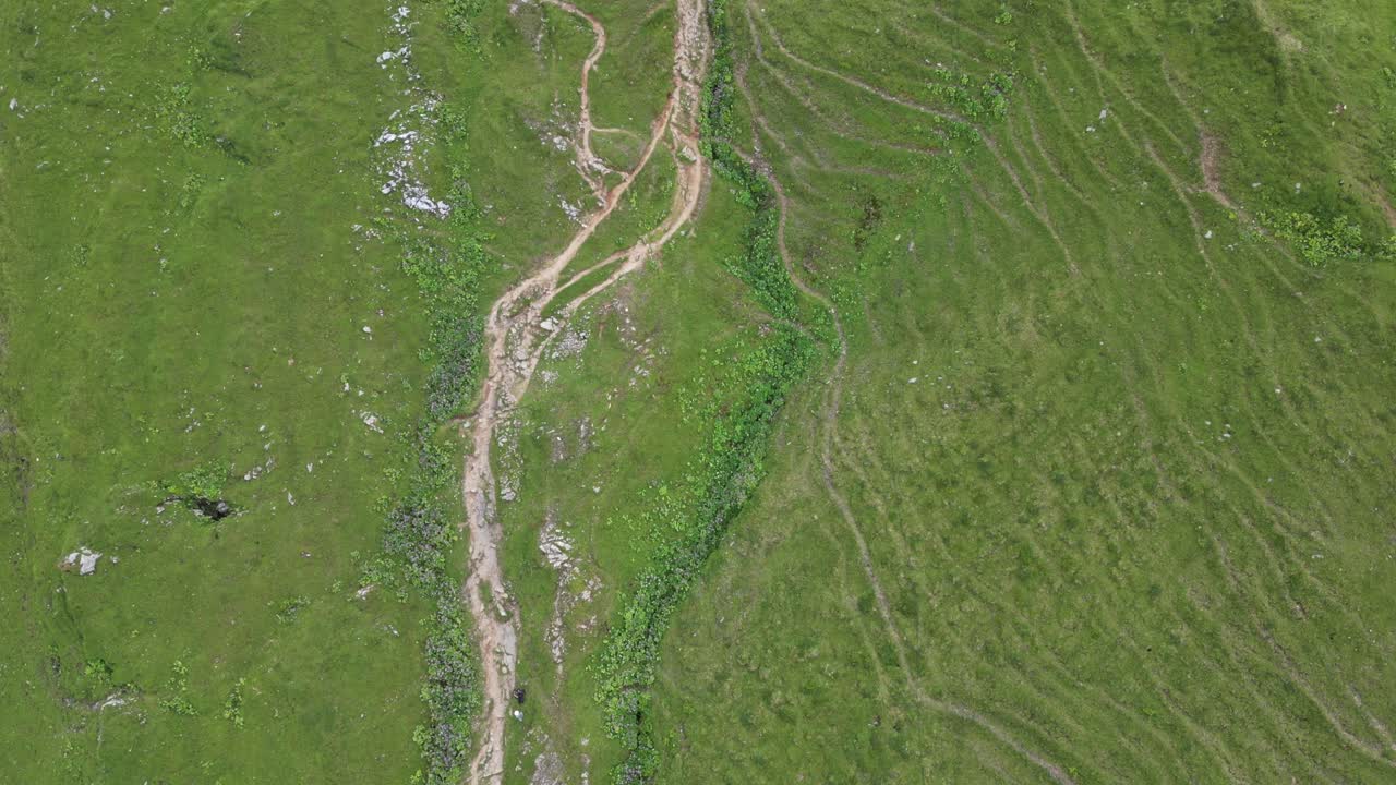 vista superior de drones de algún camino de grava natural en los alpes suizos, prados verdes, obwalden, engelberg