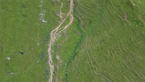 Vista-Superior-De-Drones-De-Algún-Camino-De-Grava-Natural-En-Los-Alpes-Suizos,-Prados-Verdes,-Obwalden,-Engelberg