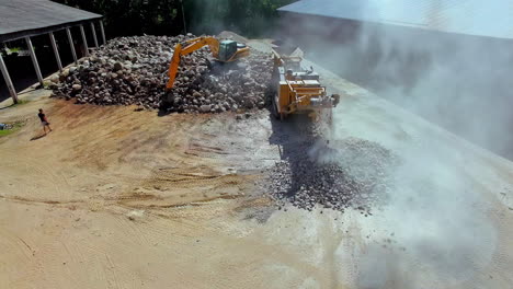 disparo de drones: aumento de polvo en el aire durante el trabajo en el sitio de construcción con excavadora y transportador