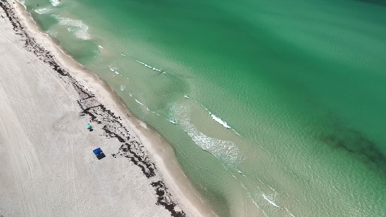 Vertically tilted aerial view of a pristine sandy beach with turquoise water and amazing waves, Panama City Beach, Florida, USA