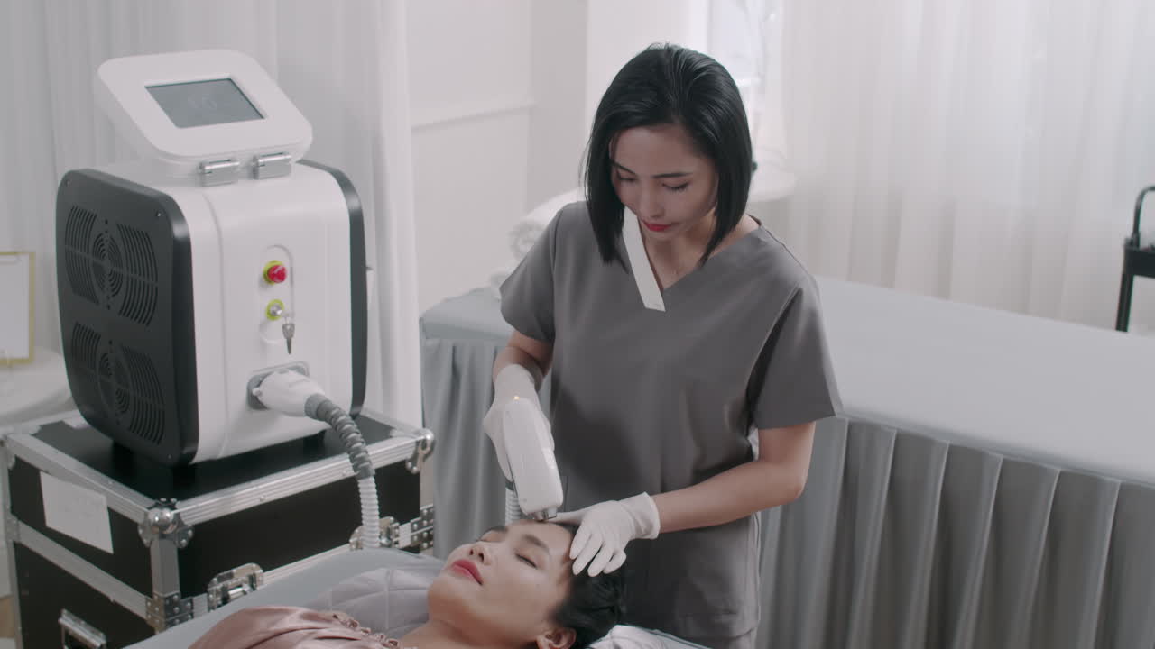 Beauty Therapist Giving Laser Treatment on Face of Young Client