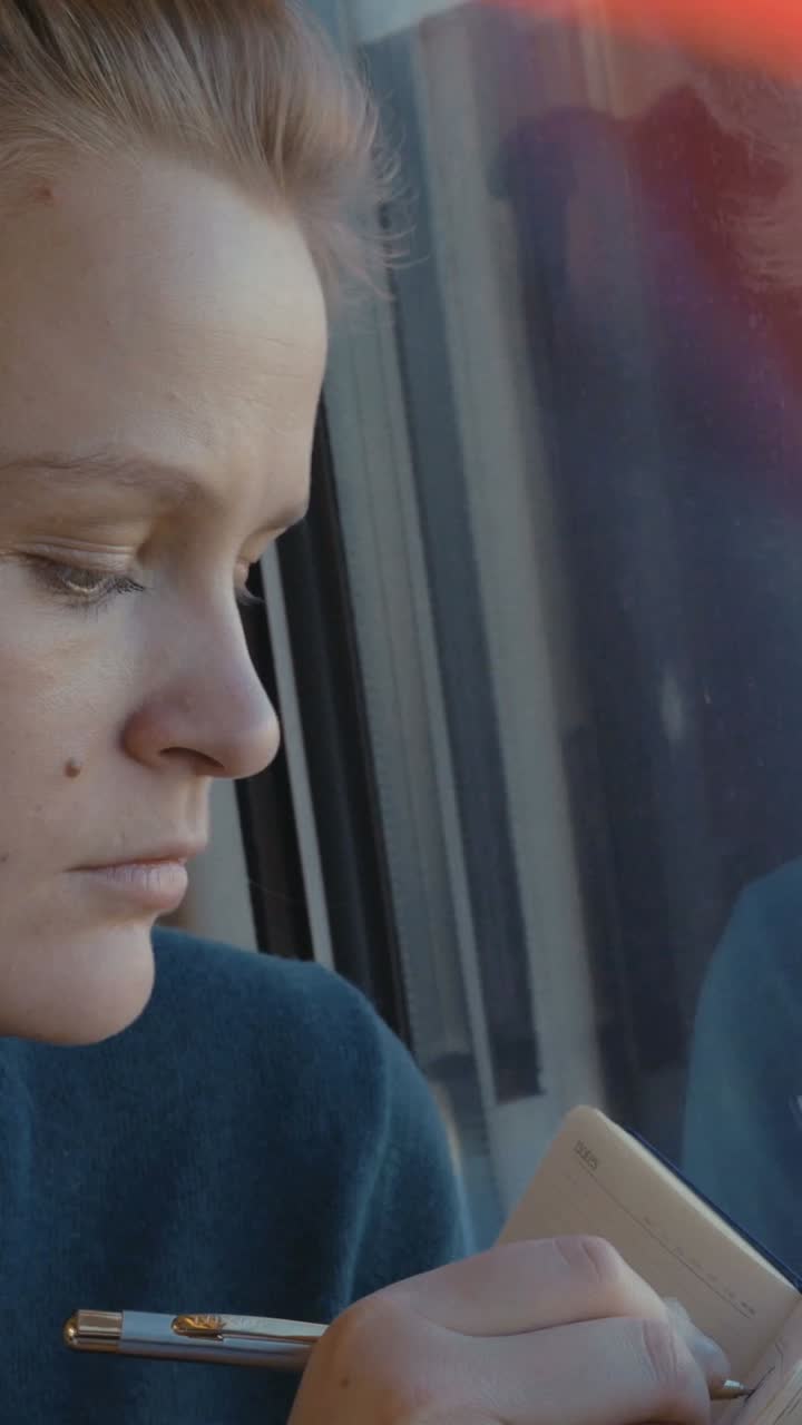 Woman writing in a notebook on a train