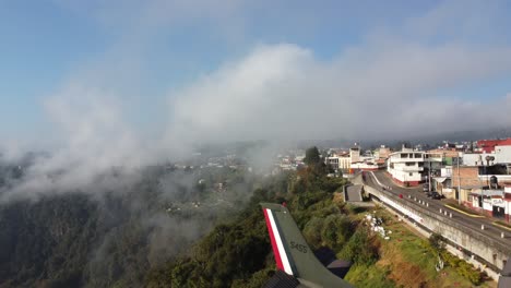 The-Cessna-252S-model-plane-from-the-Mexican-Air-Force-placed-for-tourist-attraction-with-the-rear-towards-the-ravines-of-Zacatlan,-Cityscape-in-the-atmospheric-cloud,-Puebla,-Mexico