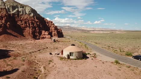 Vista-Aérea-De-Drones-De-La-Tienda-De-Yurtas-Bajo-La-Formación-De-Arenisca-De-Roca-Roja-En-El-Parque-Estatal-Del-Valle-De-Goblin,-Utah,-Ee.uu.