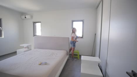 woman painting bedroom walking away from freshly painted white wall in slow motion