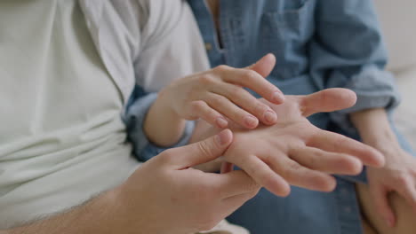 mujer irreconocible tocando tiernamente la mano de su novio mientras se sientan juntos en una alfombra en casa