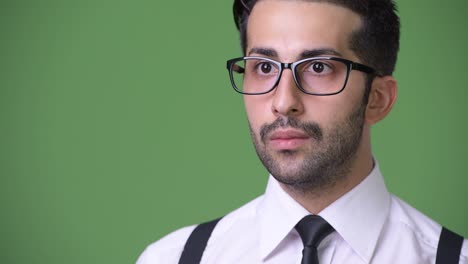 joven empresario persa barbudo y guapo contra un fondo verde