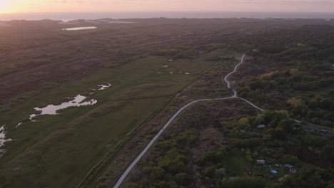 Aerial-view-of-Terschelling-island-with-dunes-and-heather-with-small-cycling-path-with-sunset