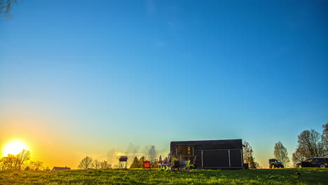 Friends-camping-in-nature-during-sunset-beside-container-cabin-house,-time-lapse