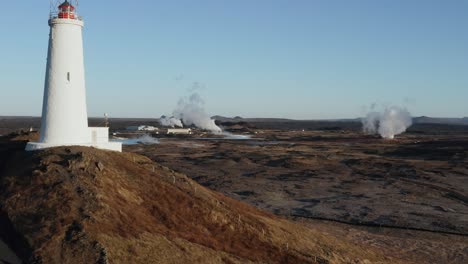 paisaje de islandia con faro remoto y gas geotérmico saliendo del campo