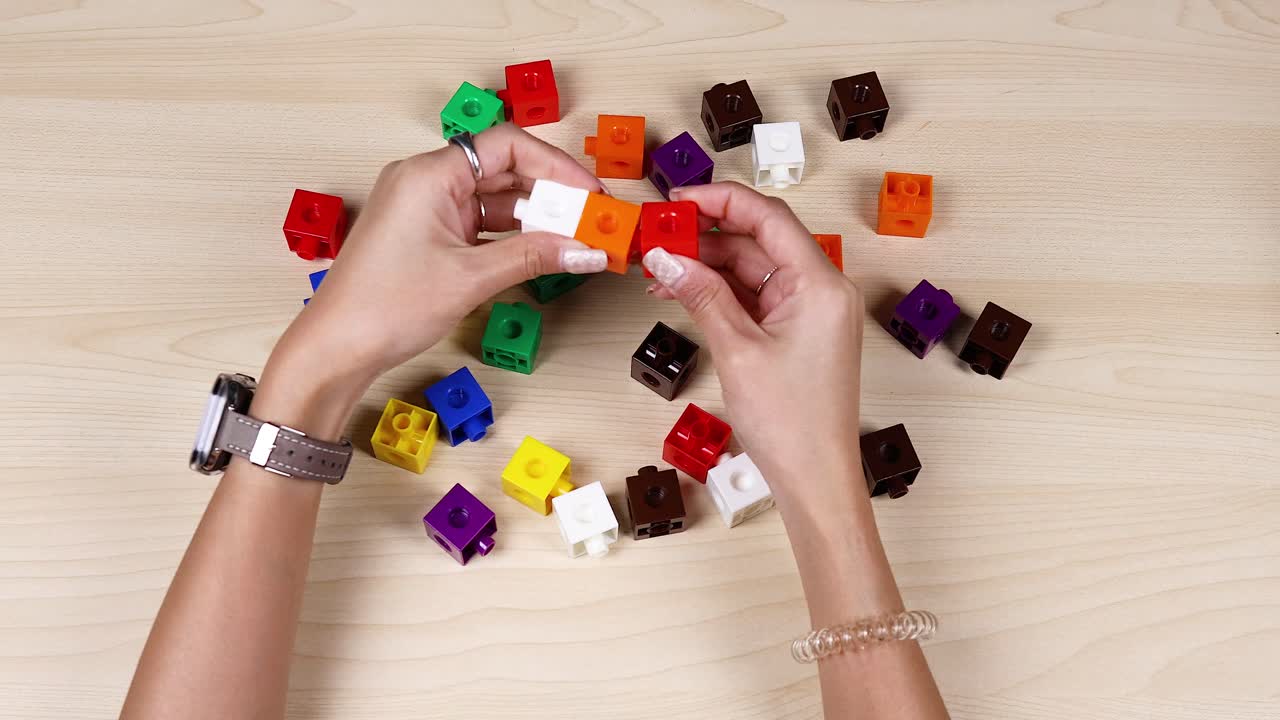 Hands assembling colorful linking cubes on a table