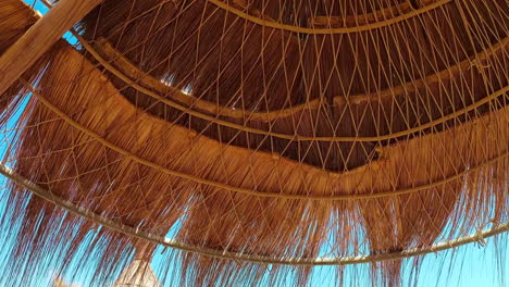 looking up at the straw made beach cottage on a sunny day -tilt up pan