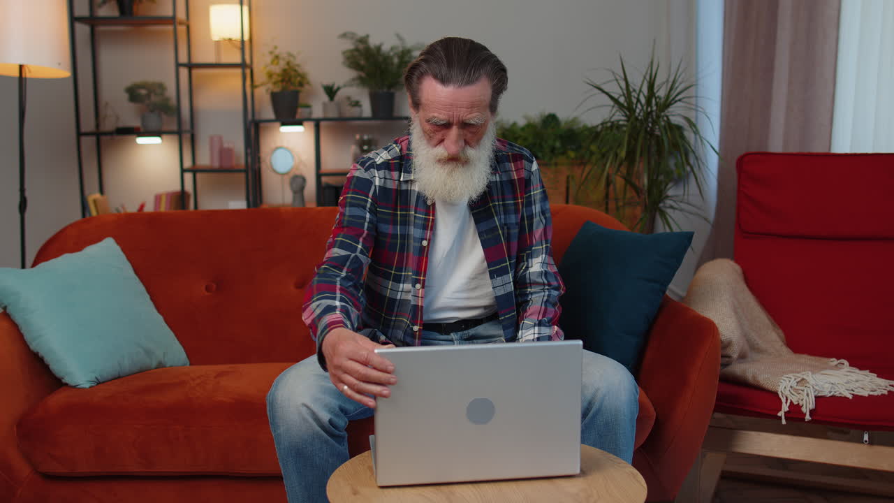 abuelo mayor hombre independiente trabajando en portátil, envía mensajes, hace compras en línea en casa
