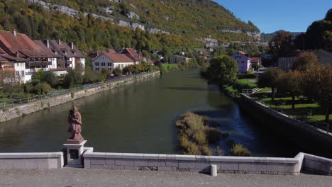 Luftaufnahme-über-Den-Fluss-Und-Die-Brücke-Der-Stadt-St-Ursanne-An-Einem-Sonnigen-Tag