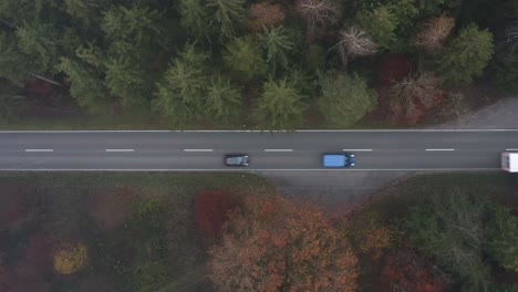 white truck is driving on a road, cars are following, drone top shot