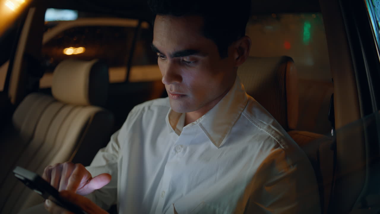 Focused director working smartphone in car closeup. Business man messaging phone