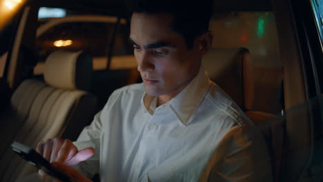 focused director working smartphone in car closeup. business man messaging phone