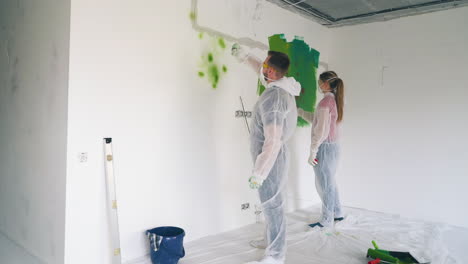 family in transparent coveralls draw on wall with sprays