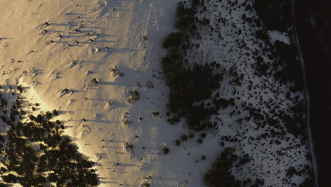 Birdseye-aerial-shot-of-snow-covered-plateau-revealing-a-wind-turbine