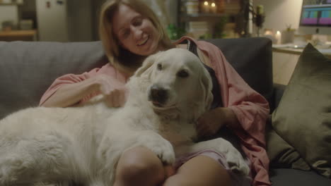 female owner petting golden retriever at home