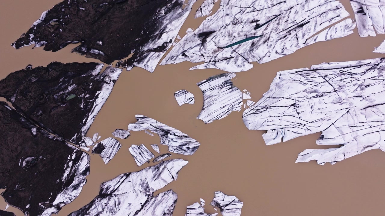 Wide top down aerial of brown water by melting glacier in Iceland