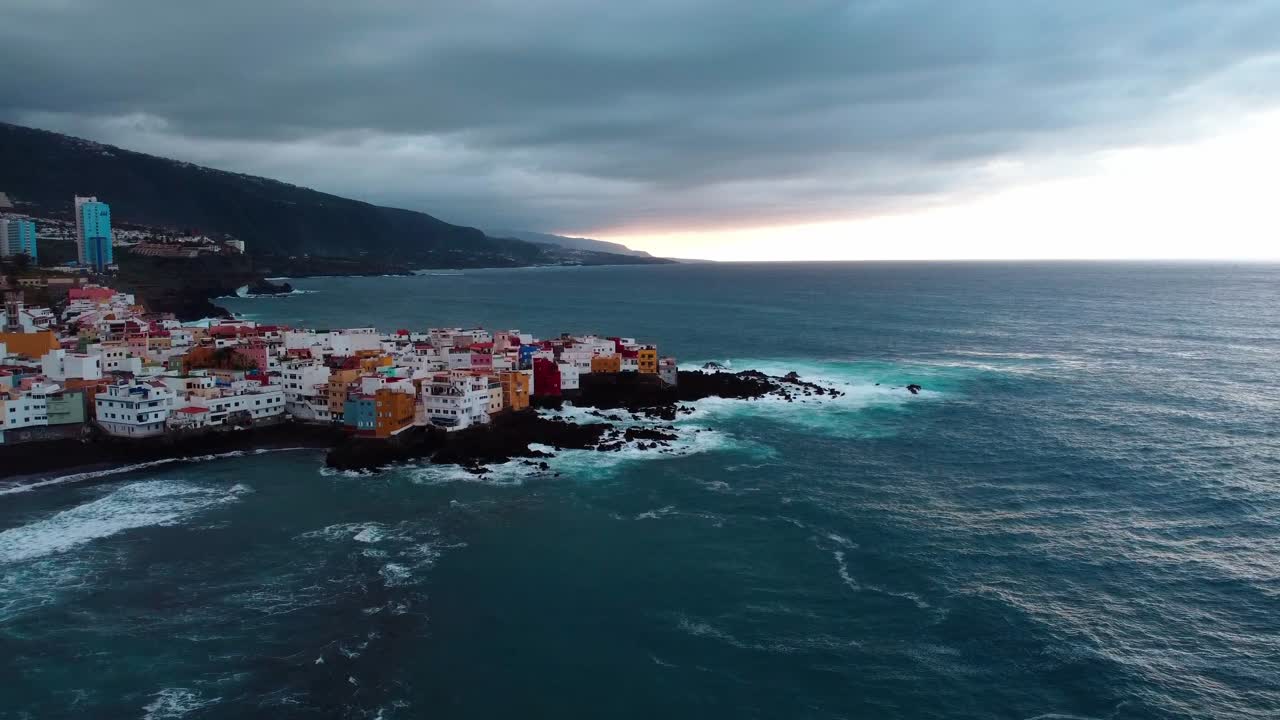 Revealing drone shot of a canary island sea city during a cloudy day and sunset