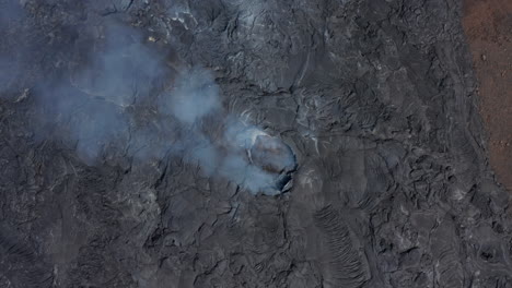 Ojo-De-Pájaro-Aéreo-Vista-De-Arriba-Hacia-Abajo-Del-Volcán-Fagradalsfjall-Agujero-De-Fisura-Del-Cráter-Humeante,-Dron-Que-Se-Levanta-Revela-Paisaje-De-Lava-Negra,-Islandia,-Día