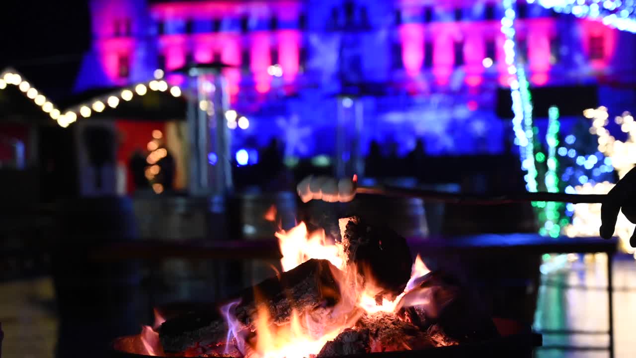 Close up of marshmallows warming up on a burning fireplace with Christmas decor on the background