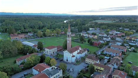 aerial view flying beside church bell tower in small italian town at golden hour
