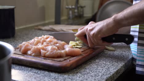 slicing garlic with chicken meat on the chopping board