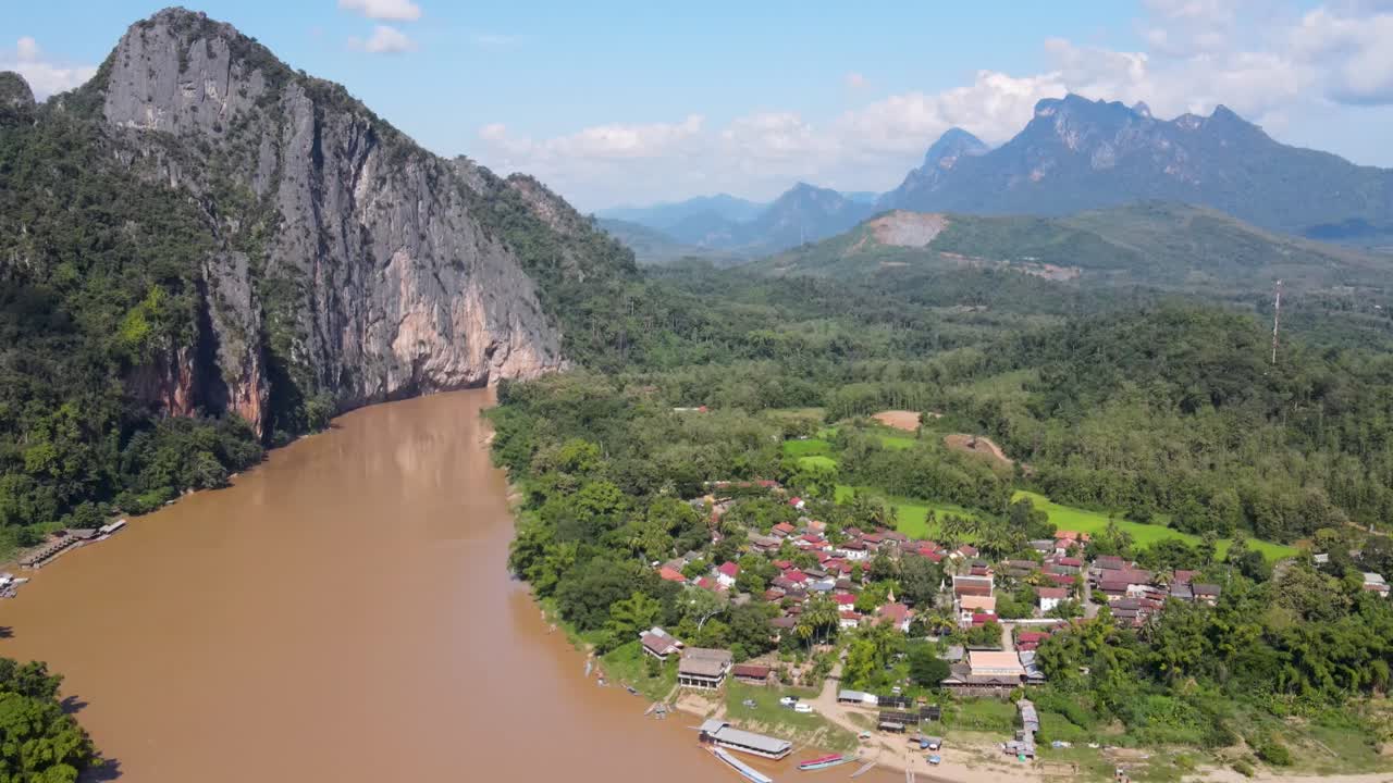 Veduta aerea del fiume Mekong accanto a un villaggio locale e a scogliere imponenti a Luang Prabang