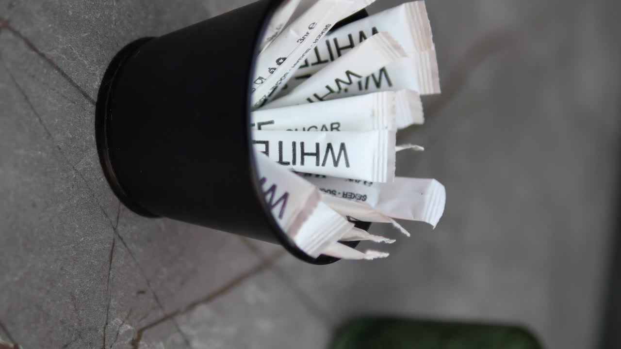 Black container filled with white sugar packets