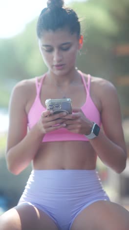 young woman in sportswear using smartphone outdoors