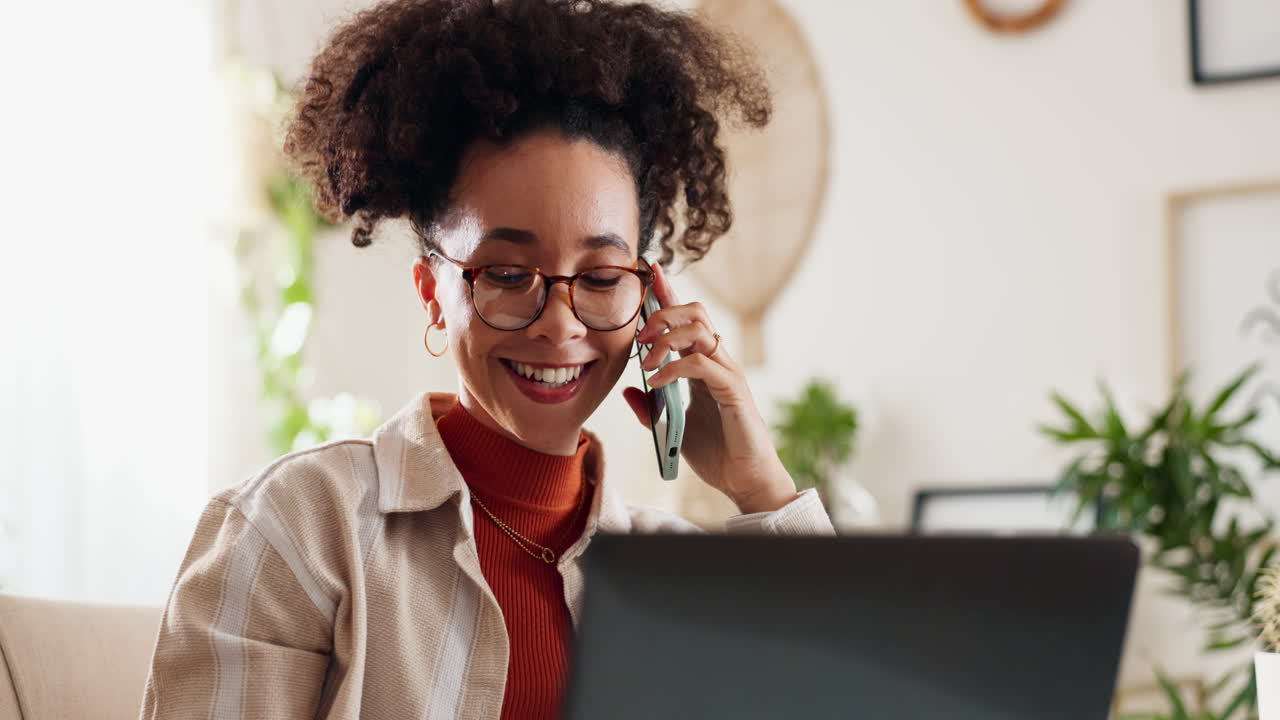 Donna che parla al telefono e lavora al portatile a casa.