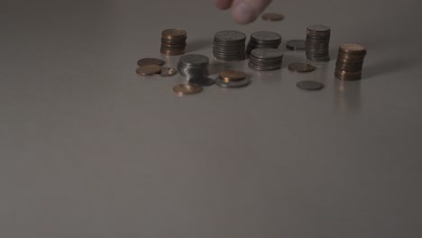 gently sweeping a pile of coins off a table to clean them up