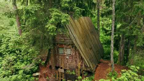 drone moves closer to wooden a-frame cabin – quiet green forest in latvia