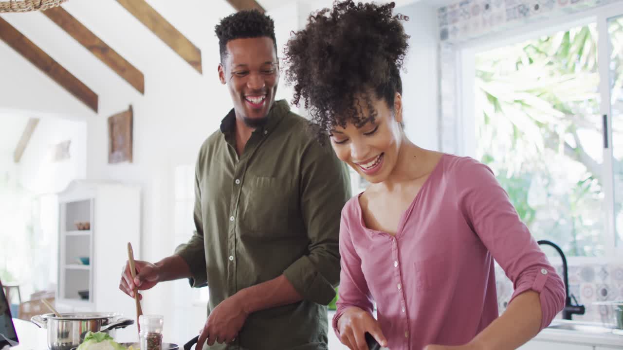 Happy african american couple cooking and talking in kitchen