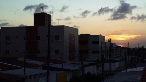 Tilt-up-shot-revealing-a-street-of-urban-apartments-of-a-poor-neighborhood-in-Joao-Pessoa,-Paraiba,-Brazil-during-a-beautiful-golden-summer-sunset