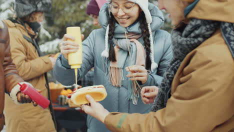 friends cooking bbq hot dogs at campsite in winter