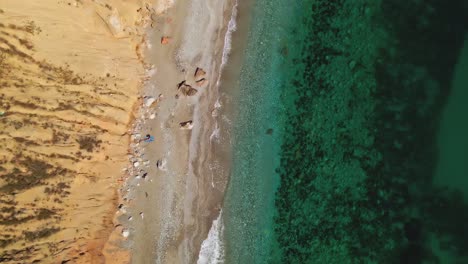 Aerial-birdseye-view-of-a-Spanish-beach,-tilting-up-into-the-horizon-on-a-clear-day