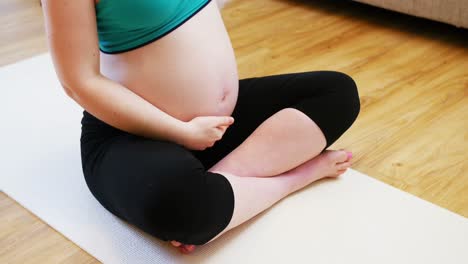 pregnant woman practicing yoga in living room