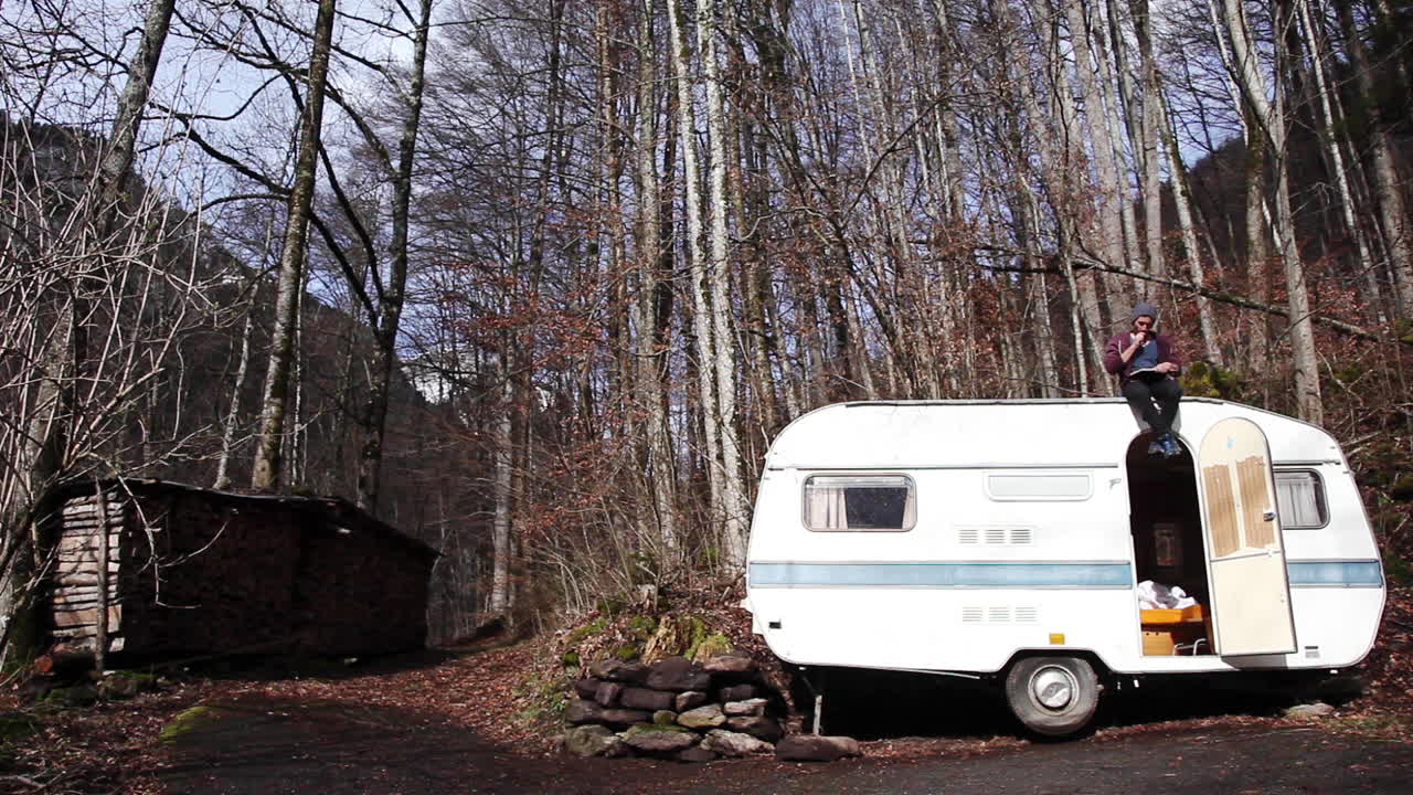 그의 밴 위에 앉아 작성하는 백인 남자
