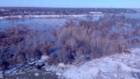 Drone-rotating-pan-shot-over-a-frozen-flooded-Audubon-Society-island-along-a-frozen-river-in-the-middle-of-winter