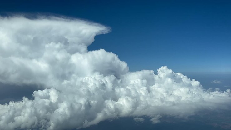 POV flying in a deep blue sky full of storm clouds seen from an airplane cockpit at cruise level