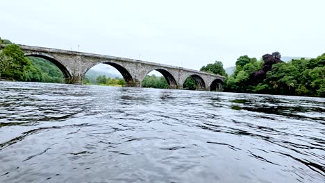 ein fließender fluss unter einer historischen steinbrücke